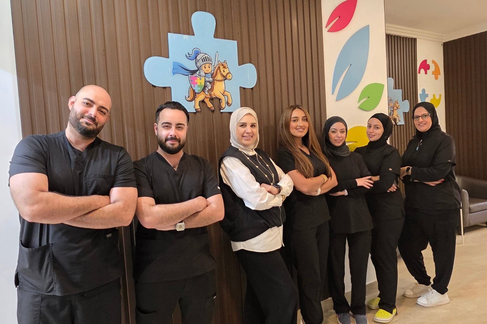 فريق مركز الفارس الصغير من الأخصائيين في مقر المركز بالسالمية أمام شعار المركز
